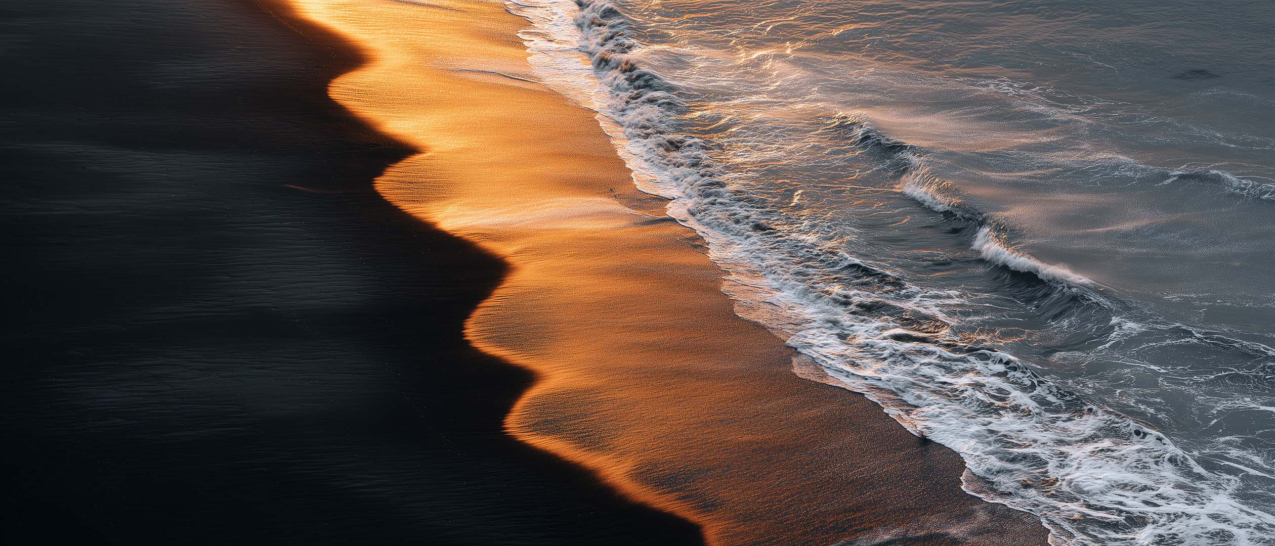 Wellen brechen sanft am Strand, während warmes Sonnenlicht die Küstenlinie in goldene Töne taucht.
